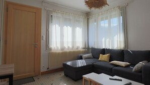 A living room with a sectional sofa, a small table, and a hanging light fixture.