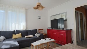 A living room with a grey sofa, a red cabinet, a TV on the wall, and a wooden table.