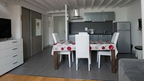 A compact living space with a dining area, kitchenette, and a television. - Cozy duplex in central La Bourboule, up to 6 people (La Bourboule)