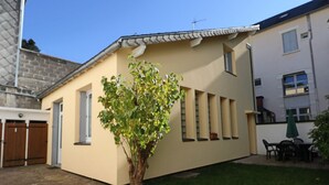 A residential building with a small tree in the front yard, a garage, and a patio area with outdoor furniture. - 2* Apartment with private garden, 4 people, in La Bourboule (La Bourboule)