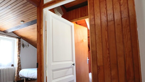 A room with a wooden ceiling, a white door, a bed, and a radiator. - 2* Apartment with private garden, 4 people, in La Bourboule (La Bourboule)