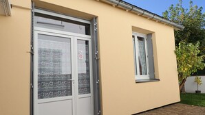 A building with a beige exterior, a double door with frosted glass panels, and a small window. - 2* Apartment with private garden, 4 people, in La Bourboule (La Bourboule)