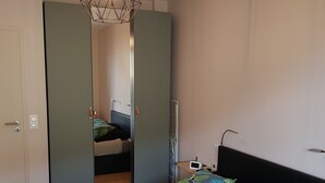 A bedroom with a bed, a wardrobe, a bedside table, and a mirror. - Apartment with large sunny terrace, close to spa and skiing (Mont-Dore)