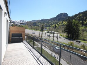 A balcony with a view of a road, a mountain, and a forest. - Charming Scandinavian apartment with parking in Mont-Dore (Mont-Dore)