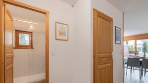 A hallway with wooden doors, a framed picture on the wall, and a window with a view of the outside.