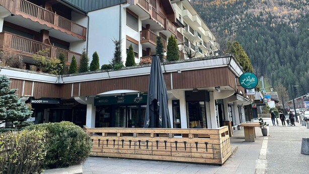 A multi-story building with balconies, a cafe, and a restaurant named 'Resto L'Alt'.