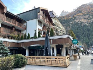 A multi-story building with balconies, a cafe, and a restaurant named 'Resto L'Alt'. - Central apartment with terrace, parking, 4 pers. (Chamonix-Mont-Blanc)