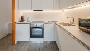 A modern kitchen with white cabinets, a built-in oven, a microwave, and a coffee maker.