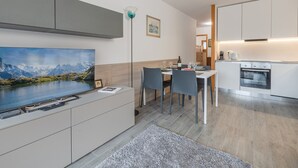 A modern kitchen with white cabinets, a built-in oven, and a dining area with a table and chairs.