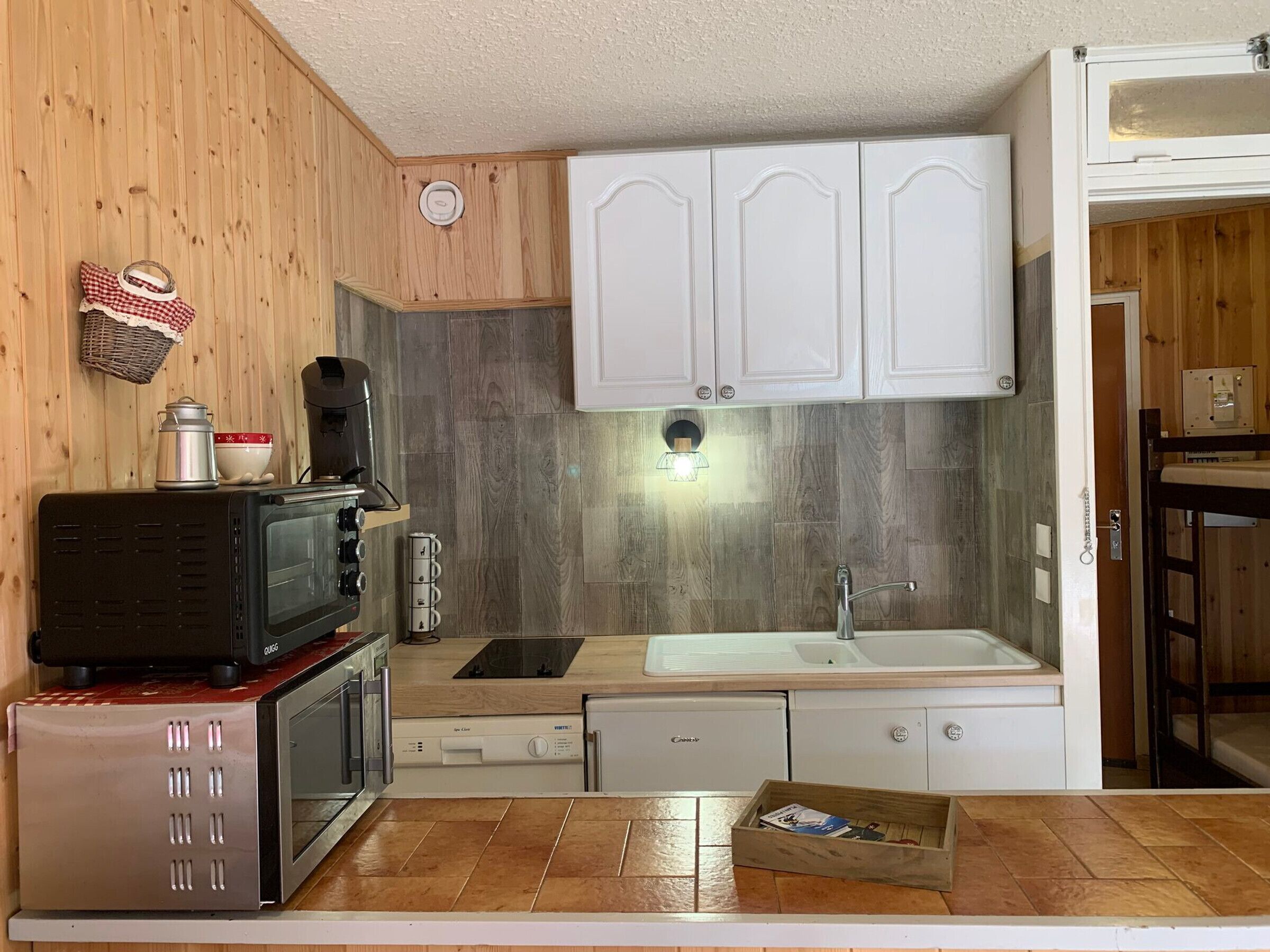 A compact kitchen with a microwave, coffee maker, and a sink.