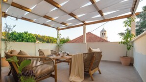 Un patio al aire libre con mobiliario de mimbre, una mesa con bebidas y plantas en macetas.