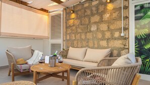 Un espacio al aire libre acogedor con muebles de mimbre, un sofá con cojines y una mesa de madera.