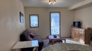 A compact living space with a sofa, a dining table, a TV, and a kitchen area. - Family chalet for 10 people with parking in Cauterets (Cauterets)