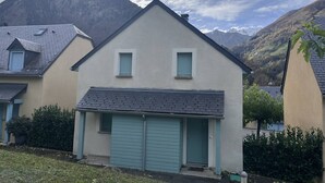 A two-story house with a garage, surrounded by mountains and greenery. - Family chalet for 10 people with parking in Cauterets (Cauterets)