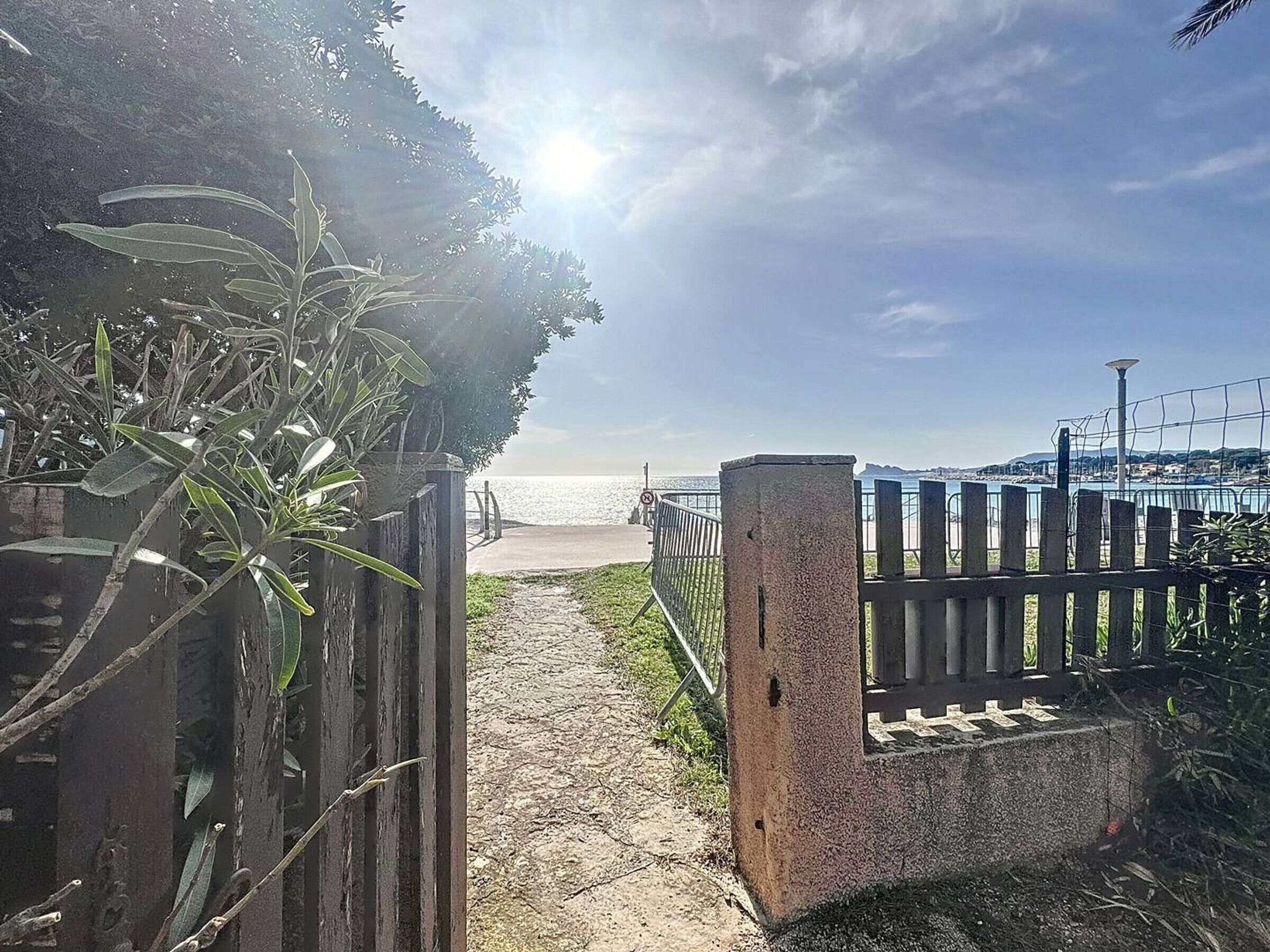 A pathway leading to a beach with a wooden fence and a concrete barrier.