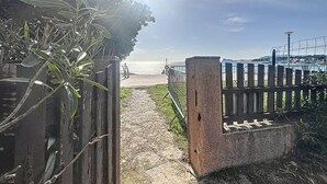 Un sentier menant à une plage, bordée d’une clôture en bois et d’une barrière en béton.