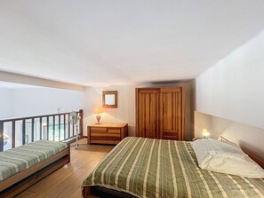 Une chambre à coucher comprenant un lit, une table de chevet, une armoire en bois et un balcon.