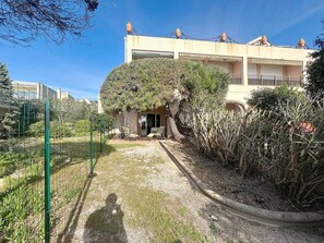 Un immeuble résidentiel doté d’un patio couvert, d’un jardin clôturé et offrant une vue sur un ciel dégagé.