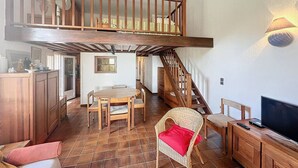 Un vaste loft doté d’un escalier en bois, d’un coin repas et d’un téléviseur posé sur un meuble en bois.