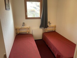 A small, single-room accommodation with two single beds, a window with a view, and a radiator. - Orcières Merlette, 3 rooms, 6 pers, 42m², WIFI, Parking (Orcières Merlette)