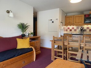 A compact living space with a sofa, a dining table with chairs, a kitchen area with wooden cabinets, and a small potted plant. - Orcières Merlette, 3 rooms, 6 pers, 42m², WIFI, Parking (Orcières Merlette)