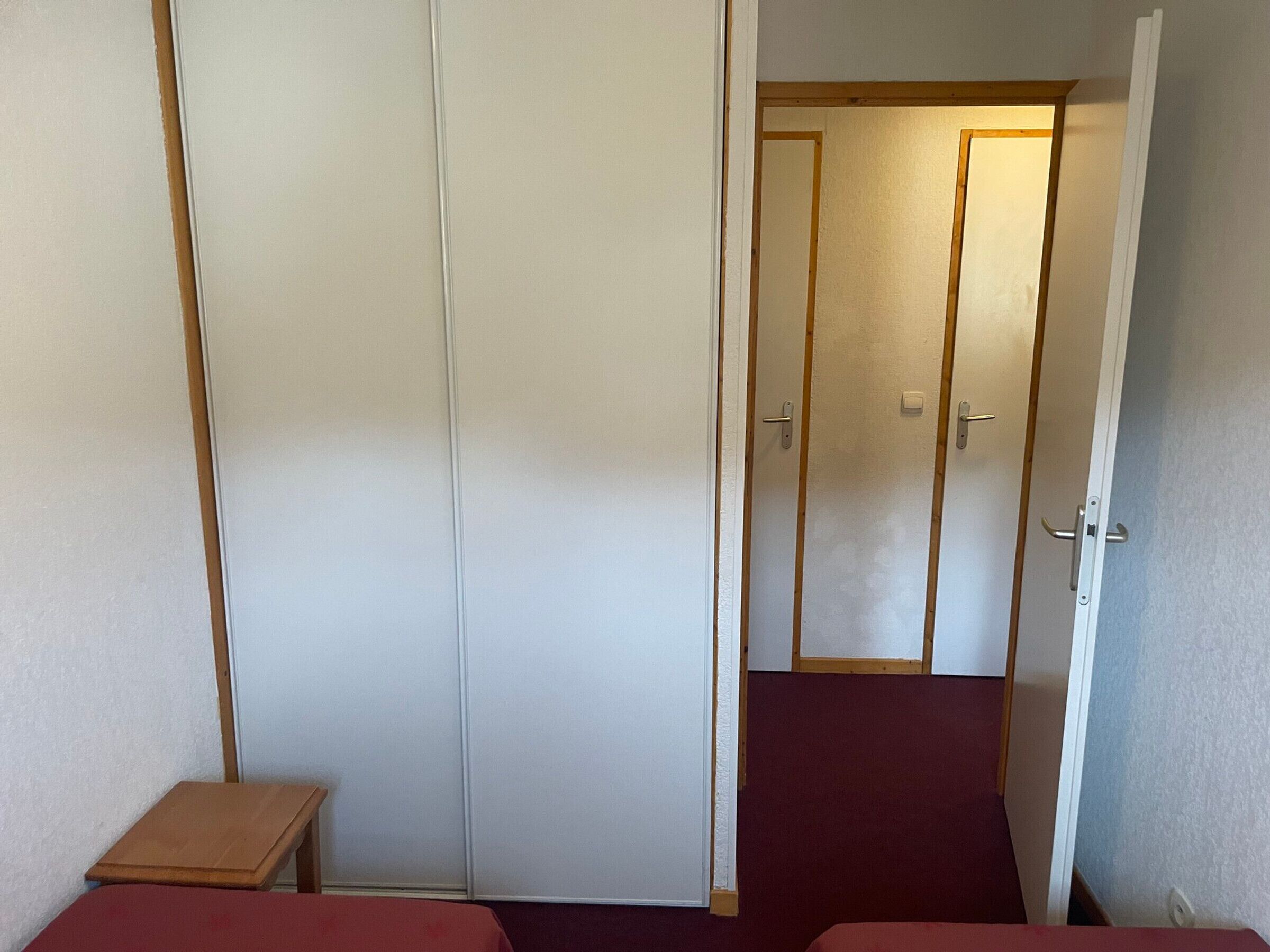 A room with a single bed, a small table, and a wardrobe.