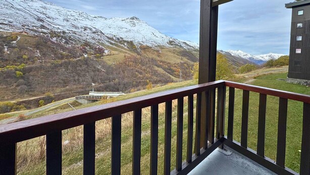 Ein Balkon mit Blick auf verschneite Berge und ein Gebäude in der Ferne.