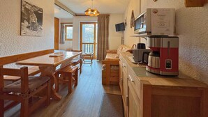 Eine gemütliche Küche mit Holzmöbeln, einer Kaffeemaschine und einem Fernseher.