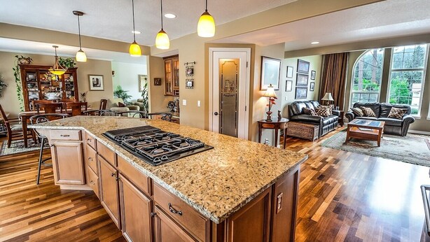 A spacious kitchen with granite countertops, wooden cabinets, and a central island. There is a dining area with a wooden table and chairs, and a living room with a sofa and coffee table. - Edinbourgh 11 (Edinburgh)