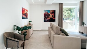 A modern living room with a sofa, armchair, and large windows. - Modern Escape Villa with Pool by ArcoCollection (St. Julian`s)