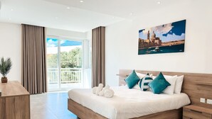 A modern hotel room with a large bed, wooden headboard, and a view of the city through large windows. - Modern Escape Villa with Pool by ArcoCollection (St. Julian`s)