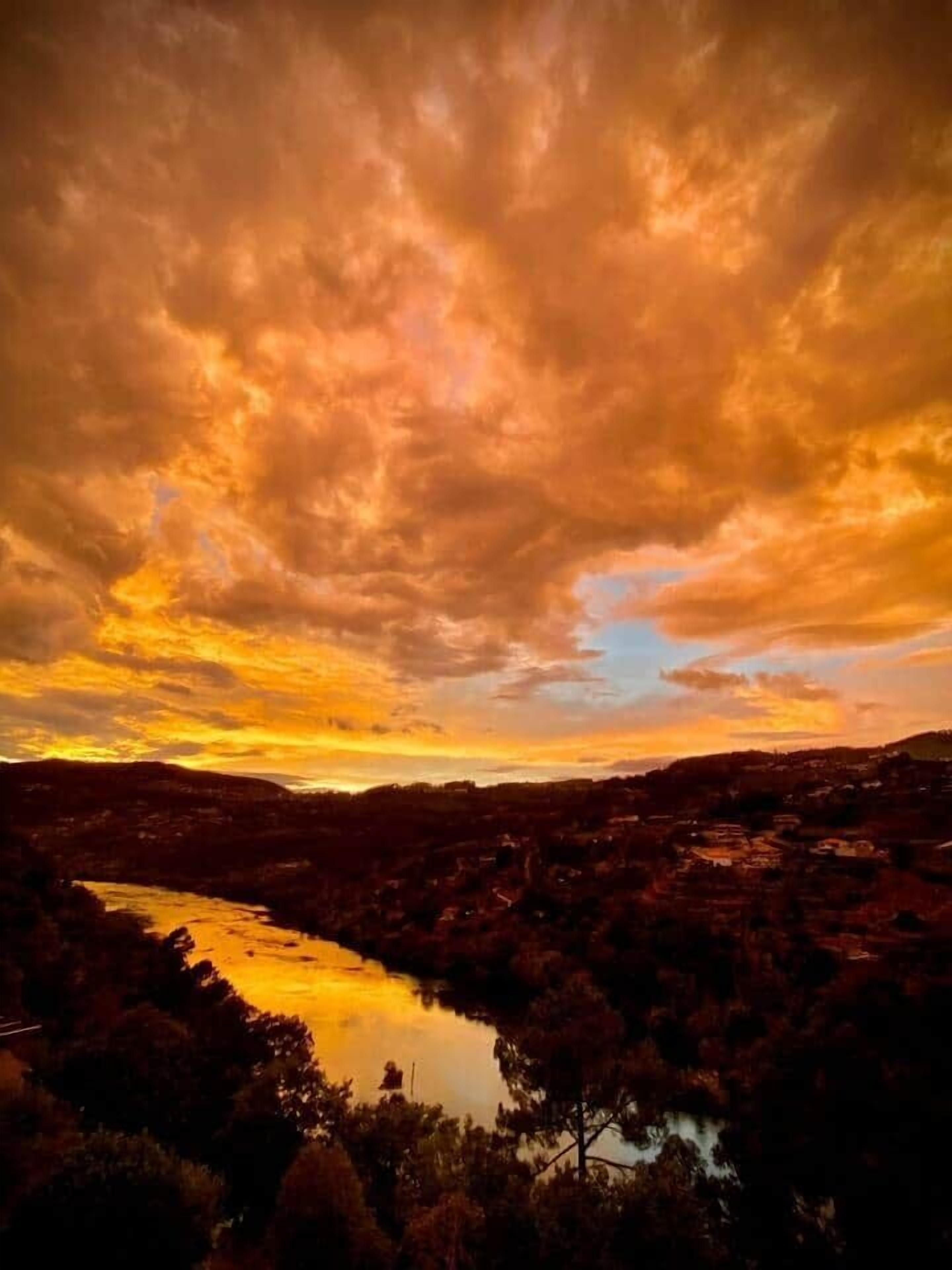 A sunset over a valley with a lake, surrounded by hills.