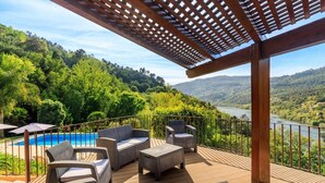 A deck with wicker furniture overlooking a swimming pool and a scenic view of a river and hills. - Villa in the Douro - Quinta de Pias. Perfect for families! (Espadanedo)