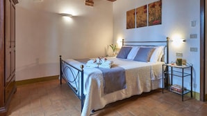 Ein Schlafzimmer mit einem Bett, einem Nachttisch, Wandbildern und einer Holzbalkendecke.