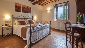 Ein Schlafzimmer mit einem Bett, einem Nachttisch, einem Fenster mit Blick und einem Sessel.
