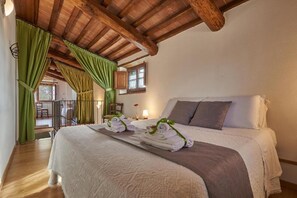 A bedroom with a wooden ceiling, a bed with a white comforter, and a view of a balcony. - Agriturismo Bonello Flat 3 Bedrooms with Pool, Private Terrace and Wi-Fi (Pienza)