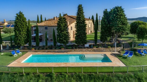 A pool with a clear blue water, surrounded by a fence, and a building with a tiled roof in the background. - Agriturismo Bonello Flat Standard Apartment with Pool, Shared Garden and Wi-Fi (Pienza)