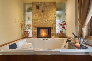 Un baño con pared de piedra, chimenea y bañera.