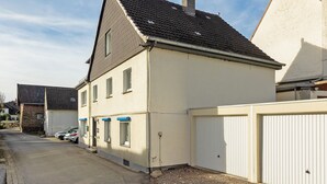 En bostadsbyggnad med ett sluttande tak, en garageport och en uppfart där bilar är parkerade.