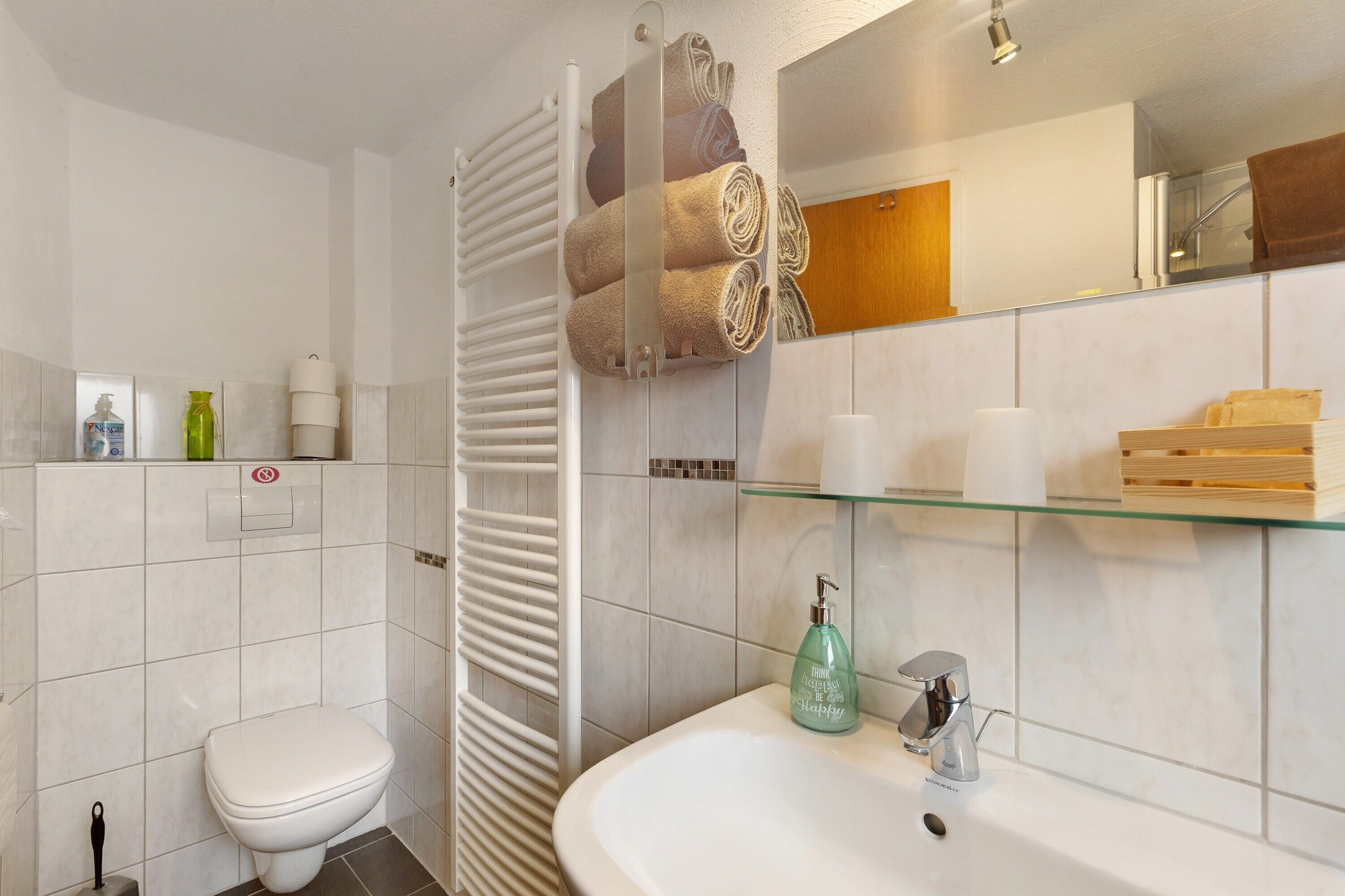 Ein Badezimmer mit Toilette, einer Duschkabine aus Glas, einem Waschbecken und einem Spiegel.