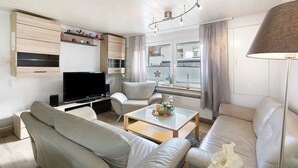 Ett modernt vardagsrum med en soffa, ett soffbord, en tv och en lampa.