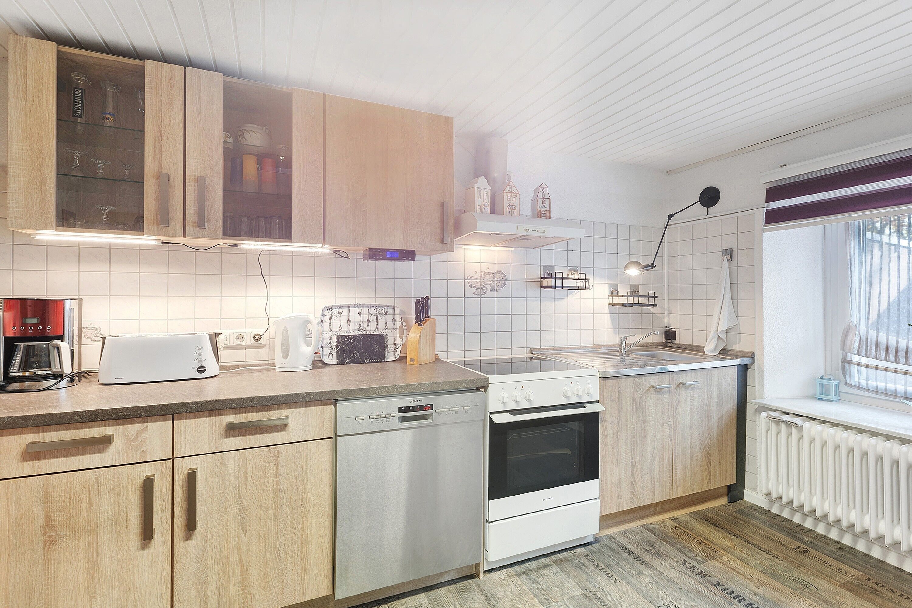 Een moderne keuken met houten kastjes, een vaatwasser, een oven en een raam met uitzicht.
