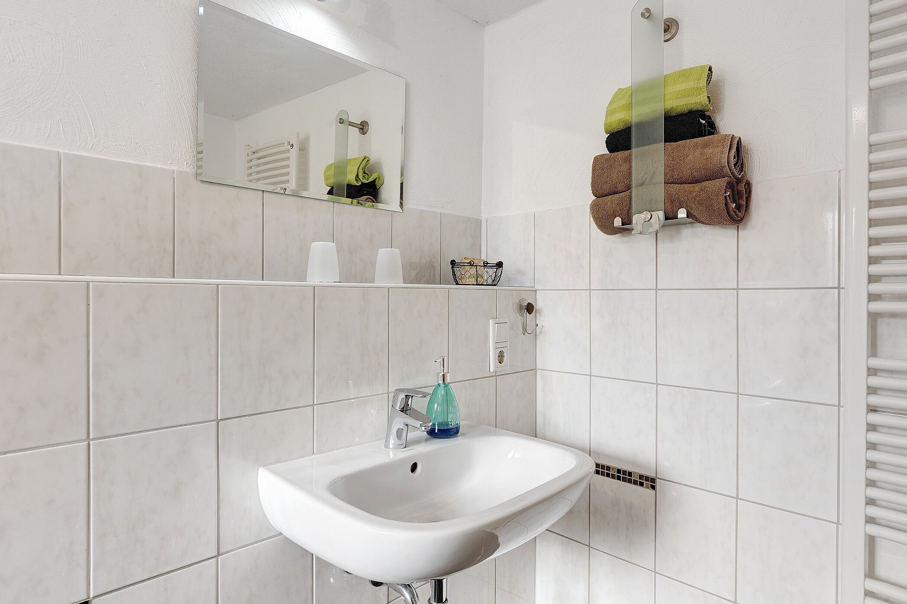Ein Badezimmer mit einem weißen Waschbecken, einem Spiegel und einem Handtuchhalter mit Handtüchern.