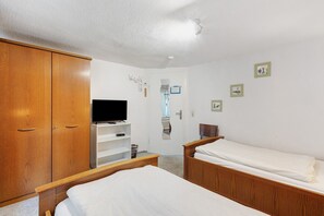 A bedroom with two single beds, a wooden wardrobe, a television on a stand, and a door with a mirror. - Room '2_Twin Room No. 2' with Wi-Fi (Neuenrade)