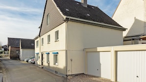 En bostadsbyggnad med ett sluttande tak, en garageport och en uppfart där bilar är parkerade.