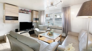 Ett modernt vardagsrum med en soffa, ett soffbord, en tv och en lampa.