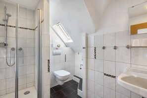 A bathroom with a shower, toilet, and sink, featuring tiled walls and a skylight. - Room '5_Double Room No. 5' with Wi-Fi (Neuenrade)