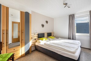A bedroom with a bed, a wardrobe, a mirror, and a window. - Room '5_Double Room No. 5' with Wi-Fi (Neuenrade)