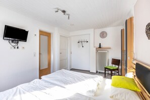 A bedroom with a bed, a television mounted on the wall, a chair, and a radiator. - Room '5_Double Room No. 5' with Wi-Fi (Neuenrade)