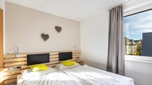 A hotel room with a bed, a TV, a bedside table, and a window with curtains. - Room '5_Double Room No. 5' with Wi-Fi (Neuenrade)